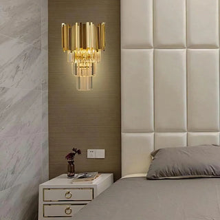 Bourbons Crystal Sconce installed above bedside table in contemporary bedroom, warm light glowing through tiered K9 crystal drops beside upholstered headboard