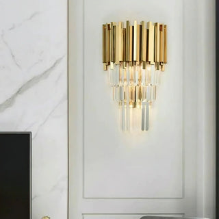 Bourbons Crystal Sconce mounted on white wall panel beside white marble wall, gold tiered crystal wall light illuminated in modern luxury living room