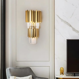 A gold crystal wall lamp is mounted on beige wainscoting; to its right stands a white marble wall, flanked by a television and a decorative gold lion figurine, complemented by a gray armchair.
