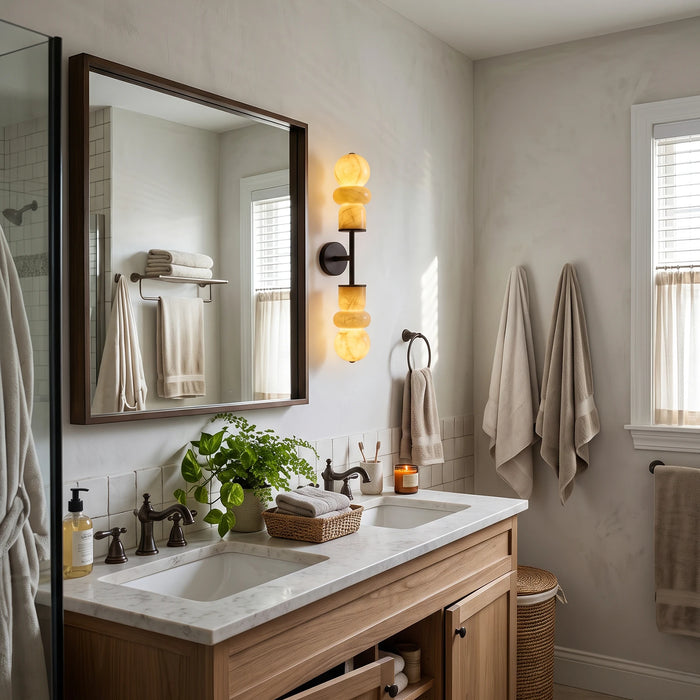 Alabaster wall sconces framing a bathroom vanity mirror