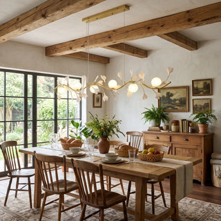 Ginkgo Vine linear chandelier over a long rustic farmhouse dining table with exposed wood beams by Vidir Lighting
