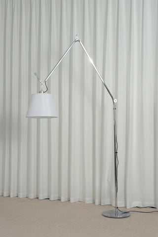 Gru Adjustable Arm Floor Lamp Vidirlighting Daylight Unlit Staged Display beside Black Accent Chair Showcasing Sleek Minimalist Silhouette