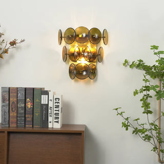 Lente Hammered Glass Disc Wall Sconce Vidirlighting Lit Showroom Display above Wooden Bookshelf with Plants Demonstrating Warm Home Accent Lighting