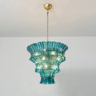 Hand holding a single curved teal blue textured glass piece for Lido chandelier by Vidir Lighting