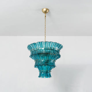 Lido teal blue tiered glass chandelier glowing against plain wall by Vidir Lighting