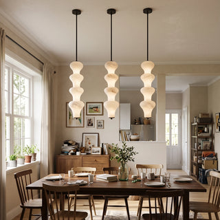 Trottola Alabaster Stacked Pendant Light Vidirlighting Linear Trio of Black Stacked Stone Pendants Casting Warm Ambient Glow over Farmhouse Dining Table